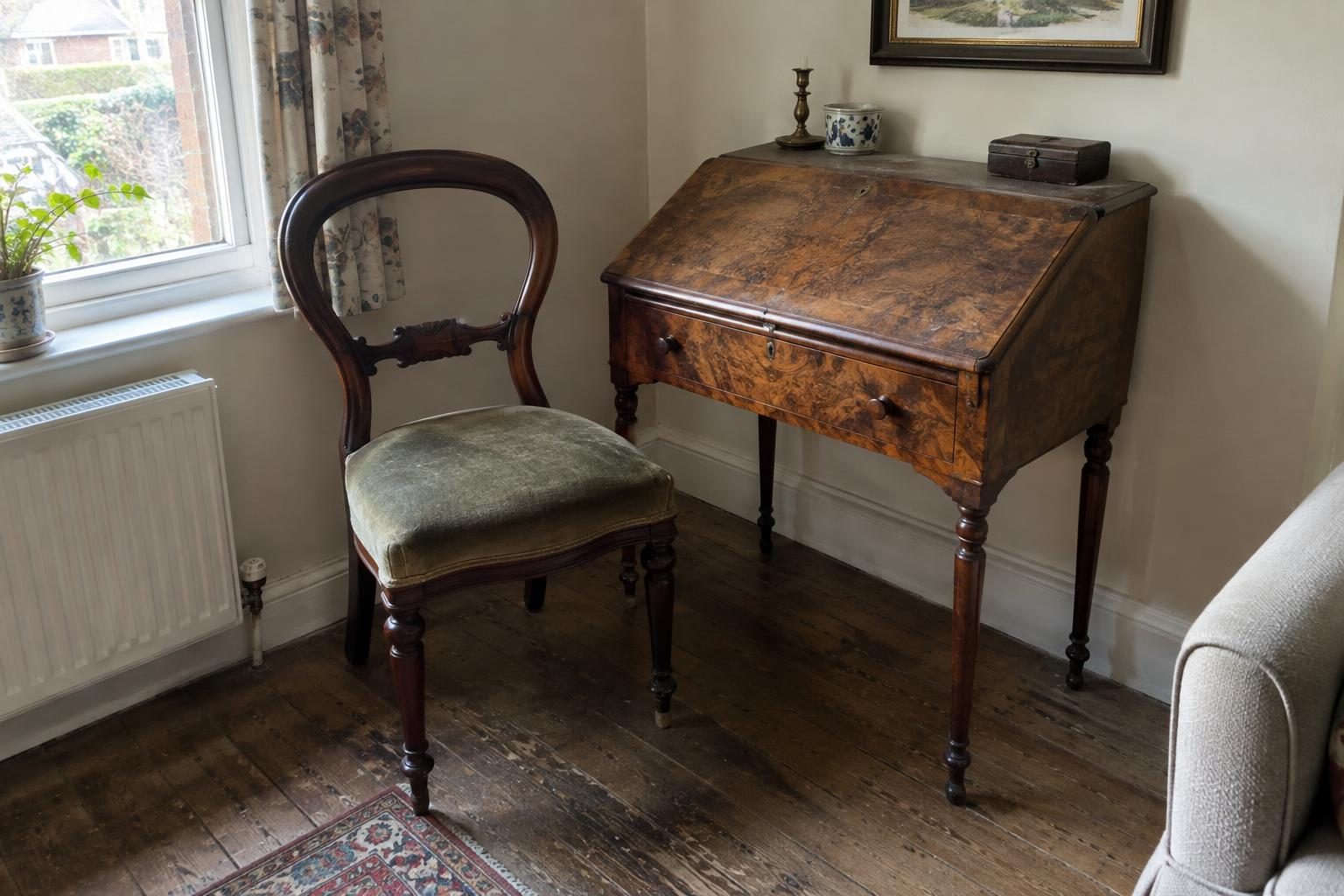 A dark walnut balloon back chair beside a small burr walnut writing desk in the corner of a living room